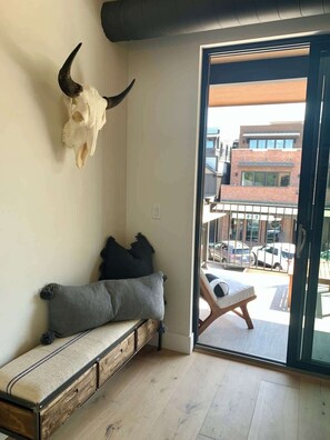 A room with a bench, a skull on the wall, and a view of a building outside. - Rooftop Patio, Downtown, 40 Mins to Glacier Park (Whitefish)