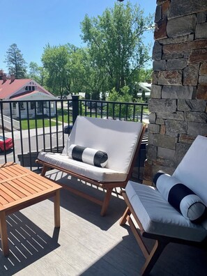 Eine Terrasse mit zwei Liegestühlen, einem Holztisch und einer Steinmauer.