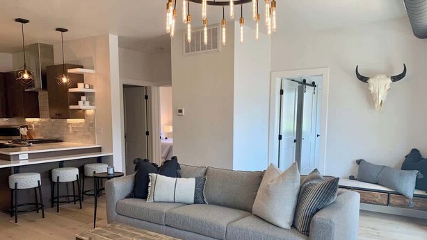 A modern living room with a sofa, coffee table, and bar stools. - Rooftop Patio, Downtown, 40 Mins to Glacier Park (Whitefish)