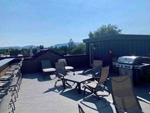 Un patio exterior con una parrilla, zona de estar y vistas a las montañas.