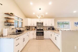A modern kitchen with white cabinets, granite countertops, stainless steel appliances, and a central island. - Cozy Desert Escape with Modern ComfortsVilla (Casa Grande)