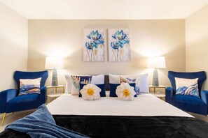 A hotel room with a large bed, two armchairs, a nightstand, and two wall-mounted lamps. - Cozy Desert Escape with Modern ComfortsVilla (Casa Grande)