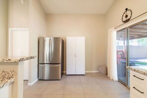 A kitchen with a stainless steel refrigerator, white cabinets, and a sliding glass door leading to an outdoor area. - Cozy Desert Escape with Modern ComfortsVilla (Casa Grande)