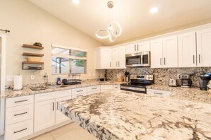 A kitchen with white cabinets, a granite countertop, a microwave, an oven, and a coffee maker. - Cozy Desert Escape with Modern ComfortsVilla (Casa Grande)
