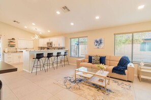 A modern kitchen with white cabinets, a central island, and bar stools. - Cozy Desert Escape with Modern ComfortsVilla (Casa Grande)