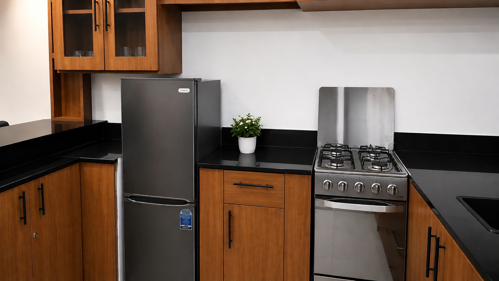 A kitchen with wooden cabinets, a stainless steel refrigerator, a gas stove, and a potted plant.