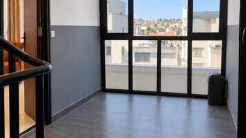 A spacious hallway with a view of a residential area through large windows.