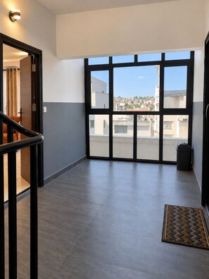 A spacious hallway with a view of a residential area through large windows.
