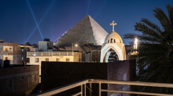 Une pyramide surmontée d’une croix, une église avec une coupole et un escalier menant à l’entrée de l’église.