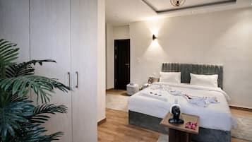Una habitación de hotel moderna con una cama grande, mesitas de noche, un armario y una planta en maceta.