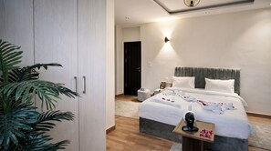 A modern hotel room with a large bed, bedside tables, a wardrobe, and a potted plant. - Villa Golden Sunset Pyramids Inn (Giza)