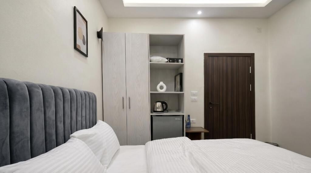 Een slaapkamer met een bed, een kledingkast, een bureau en een deur.