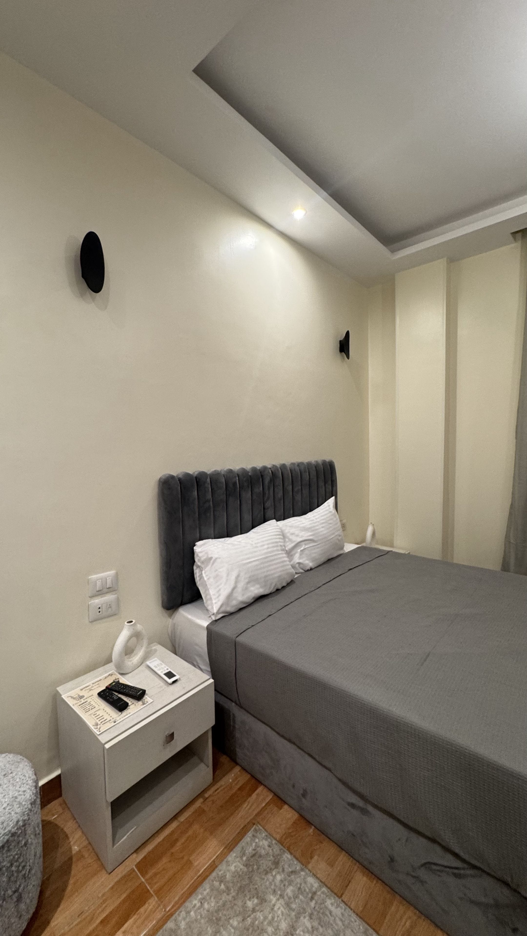 A bedroom with a bed, bedside table, and a nightstand.