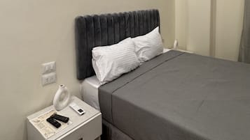A bedroom with a bed, bedside table, and a nightstand.