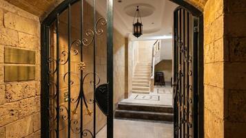 A grand entrance with a wrought iron gate, a stone wall, and a staircase leading to an upper level.