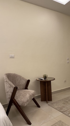 Una habitación con una silla, una mesita redonda y un interruptor de luz en la pared.
