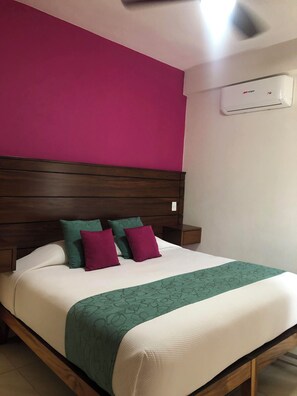A neatly made bed with a green and white bedspread, a wooden headboard, and two nightstands with a white lamp on each. - Cozy Condo with Stunning Infinity Pool (Puerto Vallarta)