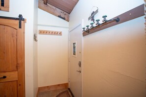 A narrow hallway with a wooden door on the left, a white door on the right, and a small window with a picture. - Irene`s Bike/HIke or Ski-In/Out! Hot Tub! Views! (Crested Butte)