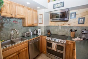 A kitchen with wooden cabinets, a stainless steel sink, a built-in oven, a microwave, and a coffee maker. - Irene`s Bike/HIke or Ski-In/Out! Hot Tub! Views! (Crested Butte)
