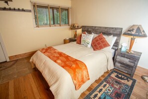 A bedroom with a bed, bedside tables, a lamp, a rug, and a window with blinds. - Columbine 1302! Ski-In/Out! Hot Tub! Views! (Crested Butte)