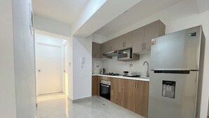 A modern kitchen with stainless steel appliances, wooden cabinets, and a tiled floor. - Apartment in Yanahuara: Modern, Central, and Fully Equipped (Yanahuara)