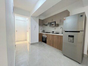A modern kitchen with stainless steel appliances, wooden cabinets, and a tiled floor. - Apartment in Yanahuara: Modern, Central, and Fully Equipped (Yanahuara)