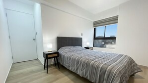 A bedroom with a bed, bedside tables, a window, and a door. - Apartment in Yanahuara: Modern, Central, and Fully Equipped (Yanahuara)