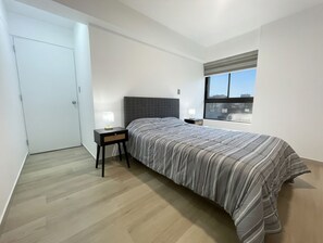 A bedroom with a bed, bedside tables, a window, and a door. - Apartment in Yanahuara: Modern, Central, and Fully Equipped (Yanahuara)