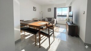 A modern living room with a dining area, a sofa, a TV, and a city view. - Apartment in Yanahuara: Modern, Central, and Fully Equipped (Yanahuara)