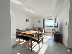 A modern living room with a dining area, a sofa, a TV, and a city view. - Apartment in Yanahuara: Modern, Central, and Fully Equipped (Yanahuara)