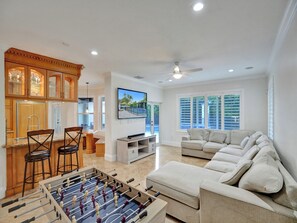 Una sala de estar con mesa de futbolín, sofá y televisor.