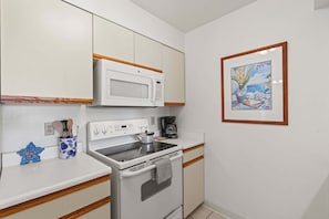 A compact kitchen with a microwave, stove, and coffee maker. - Kihei Bay Vista C-201 - Kihei 1BR Condo, AC, Lanai, Wifi, 45 Sec to Sugar Beach! (Kihei)