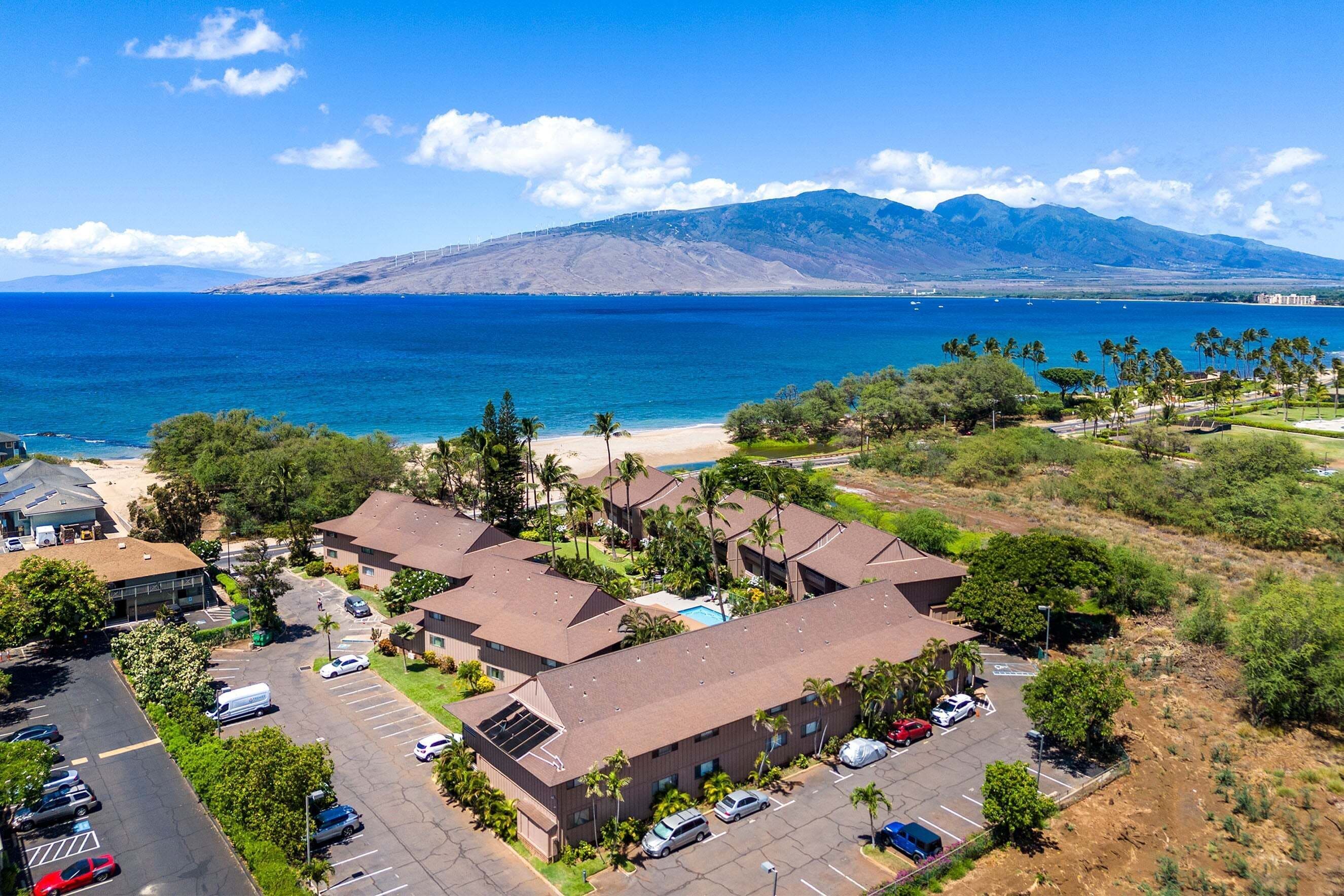 A coastal hotel with multiple buildings, parking, and a beach view.