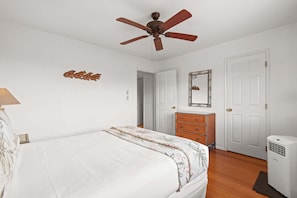 A bedroom with a bed, a ceiling fan, a dresser, a mirror, and a heater. - Kihei Bay Vista C-201 - Kihei 1BR Condo, AC, Lanai, Wifi, 45 Sec to Sugar Beach! (Kihei)