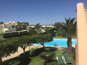 A pool area with a clear view of the pool, lounge chairs, and surrounding greenery. - Sunrays Naturist Apartment in Playas de Vera (Vera)