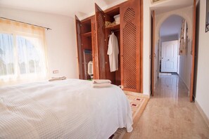 Ein Hotelzimmer mit Bett, Kleiderschrank und einem sichtbaren Badezimmer durch eine offene Tür.