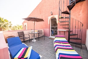 A rooftop terrace with lounge chairs, a table with chairs, a staircase, and a view of the surrounding area. - Sunrays Naturist Apartment in Playas de Vera (Vera)