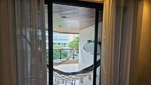 On aperçoit, à travers une porte vitrée, un balcon où est installé un hamac.