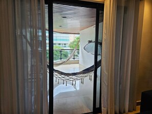 Blick durch eine Glastür auf einen Balkon mit einer Hängematte.