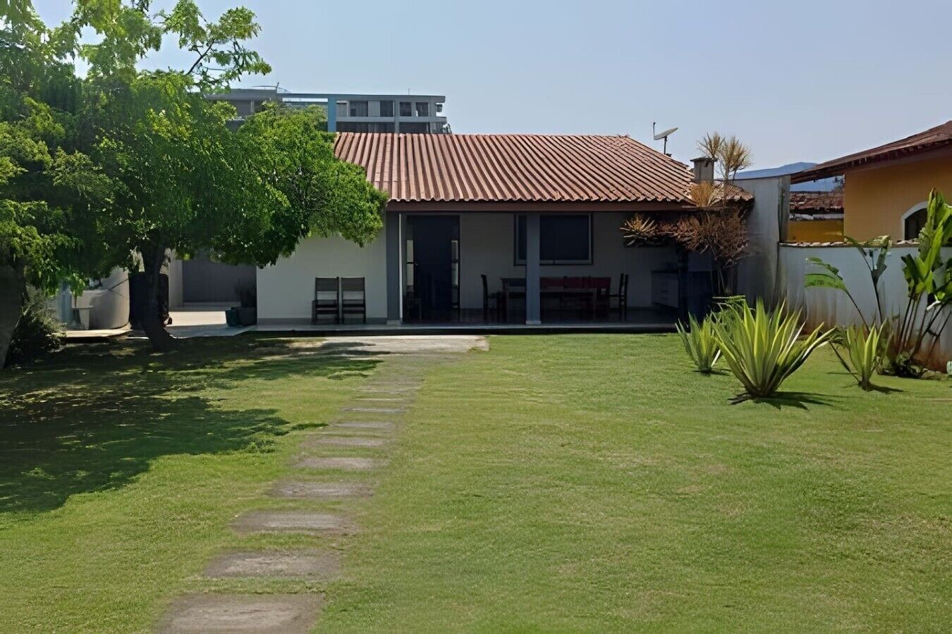 A modern house with a red roof, a paved driveway, and a well-maintained lawn.