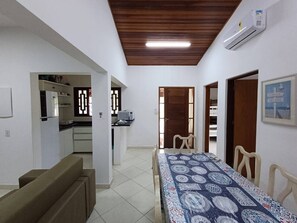 Ein Zimmer mit Esstisch, Stühlen, einer Couch, einer Küchenzeile und einem Deckenventilator.