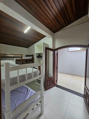 A bedroom with bunk beds, a white wardrobe, a mirror, and a door leading to an outdoor area. - Bwelcome - Casa Indaiá: Espaço Gourmet e Brisa Mar (Bertioga)