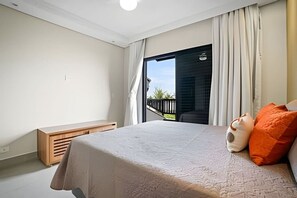 A bedroom with a bed, a bench, and a view of the outdoors. - Beachfront with pool - Costa do Sol (Loteamento Costa do Sol)