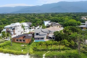 A residential area with modern houses, a swimming pool, and lush greenery. - Beachfront with pool - Costa do Sol (Loteamento Costa do Sol)