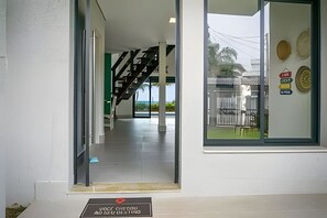 A building entrance with a staircase, a glass door, and a sign with text. - Beachfront with pool - Costa do Sol (Loteamento Costa do Sol)