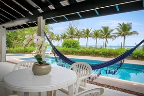 An outdoor seating area with a pool, a hammock, and a view of the ocean. - Beachfront with pool - Costa do Sol (Loteamento Costa do Sol)