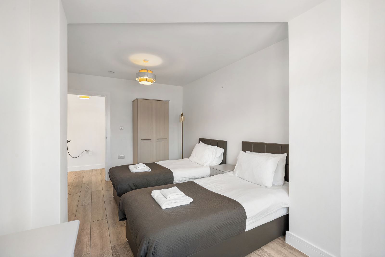 Ett hotellrum med två sängar, en garderob och en taklampa.