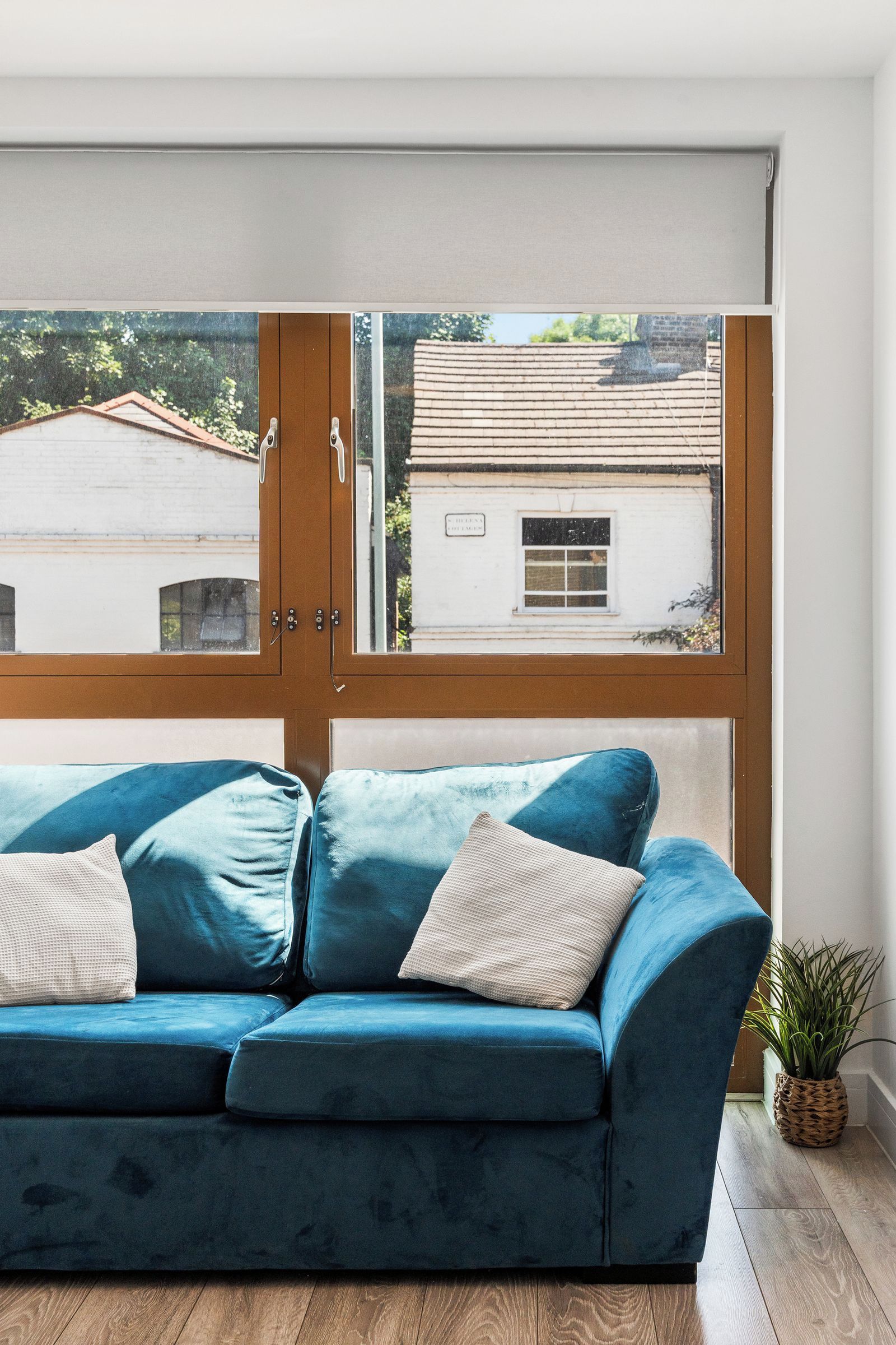 A room with a blue sofa, a wooden door, and a view of buildings through a window.
