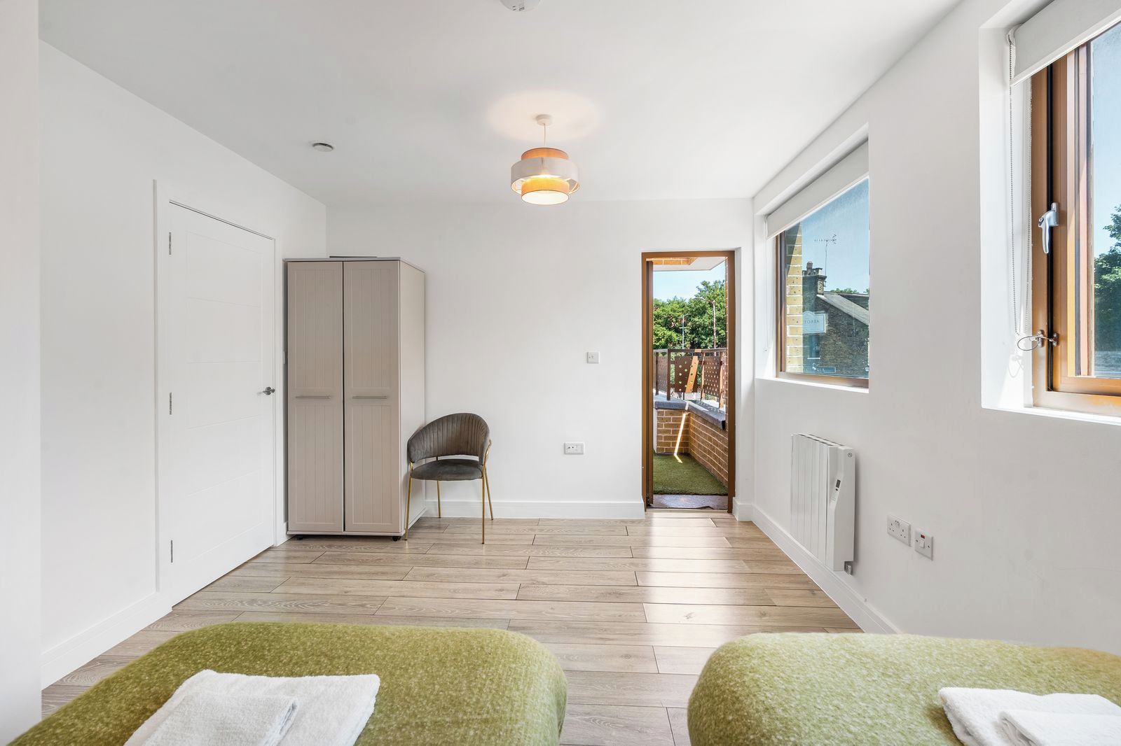 A modern room with a wardrobe, a chair, a small table, and a view of the outside.