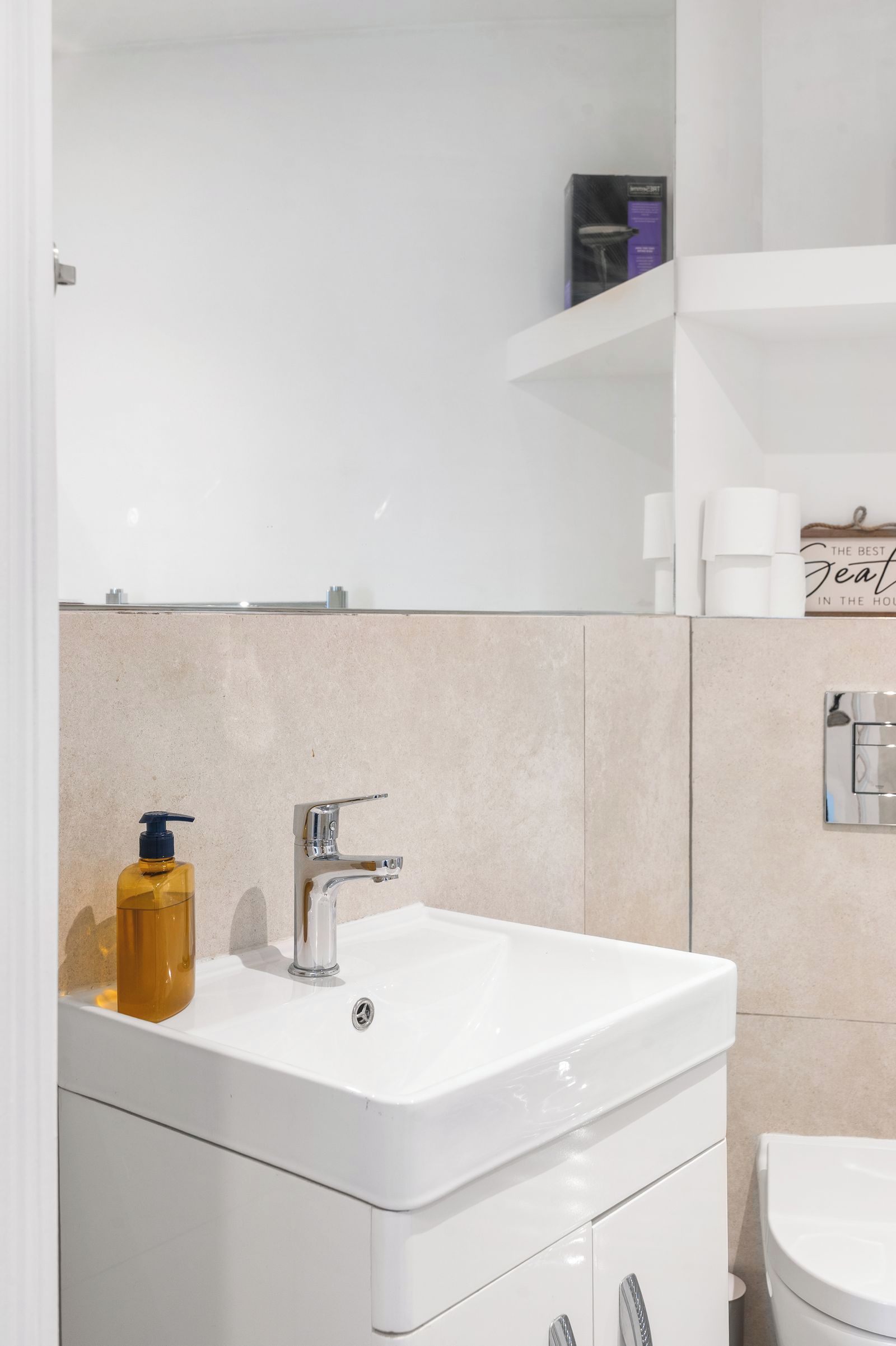 A bathroom with a white sink, chrome faucet, and a soap dispenser.